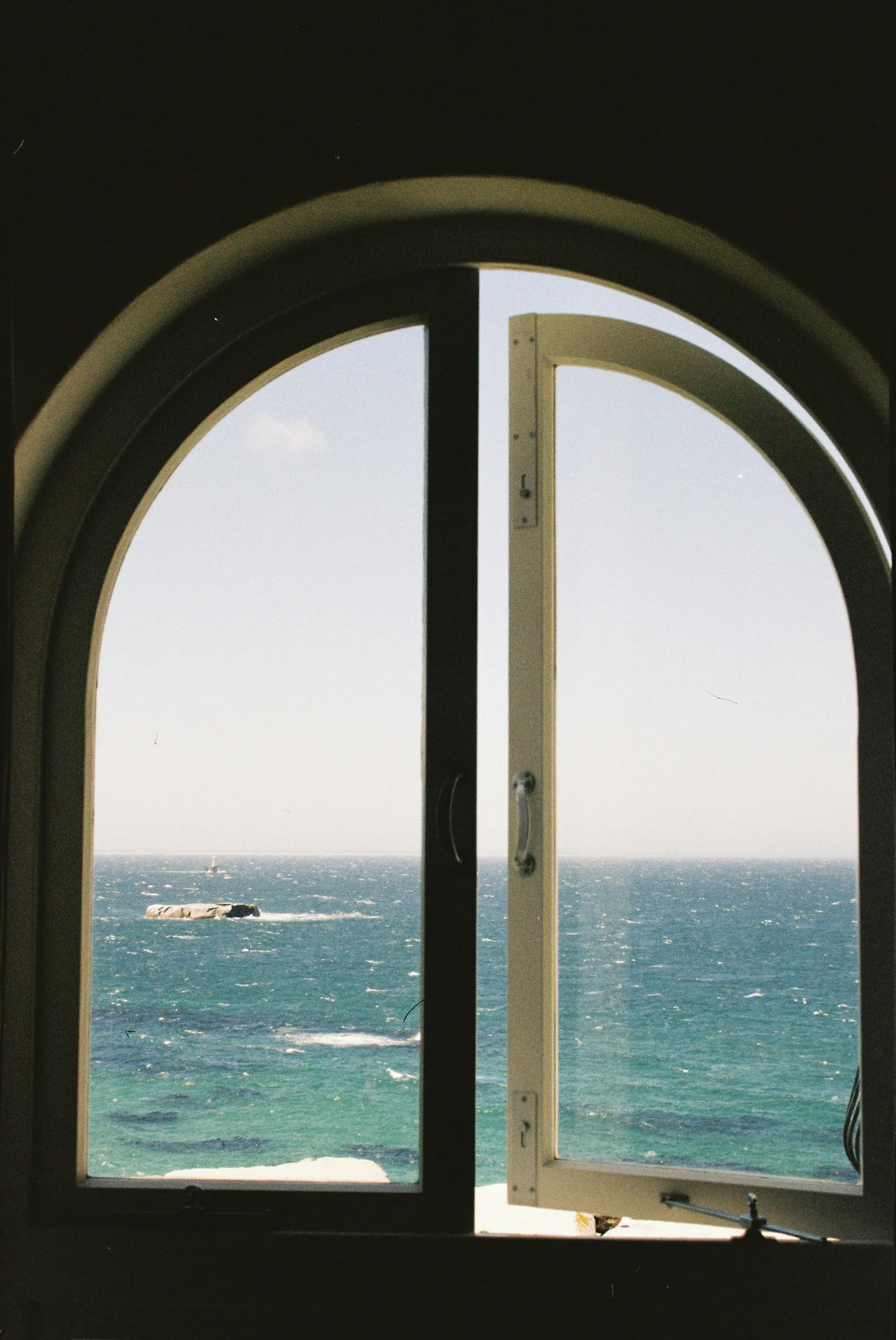 Blick durch ein Bogenfenster auf das azurblaue Meer